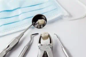 Der Zahn wird beim Zahnarzt fachmännisch mit Instrumenten gezogen.