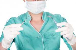 Spanischer Zahnarzt mit Mundschutz, Handschuhen und Werkzeug