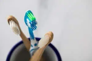 Zwei Bambus-Zahnbürsten neben einer herkömmlichen Handzahnbürste, abgebildet in einem Testbericht über Bambus-Zahnbürsten.