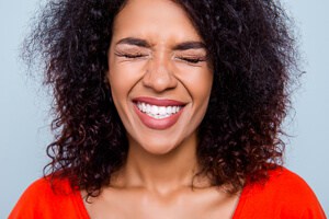 Junge Frau schneidet Grimasse mit geraden weißen Zähnen 