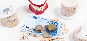 Geldscheine und Münzen symbolisieren hohe Kosten für Zahnbehandlung