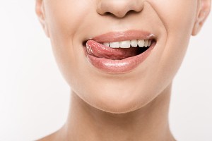 Frau fährt sich mit der Zunge über ihre Zähne