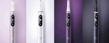 Four electric toothbrushes in different colors (gray, white, purple, black) displayed against gradient backgrounds.