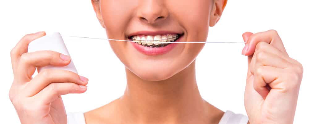 woman with braces holding dental floss