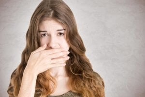 woman with halitosis covering her mouth