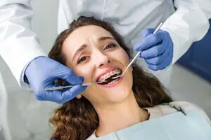 woman getting metal braces adjustment at the dentist
