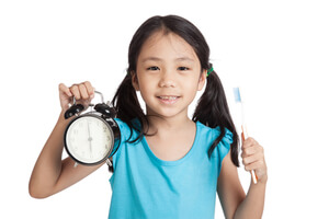 Niña sonriendo con un reloj y un cepillo dental