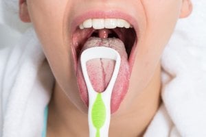 mujer con raspador de lengua