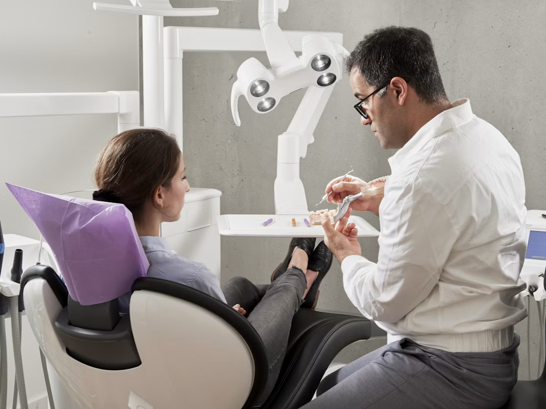 Dentist showing a patient a dental model in a treatment room