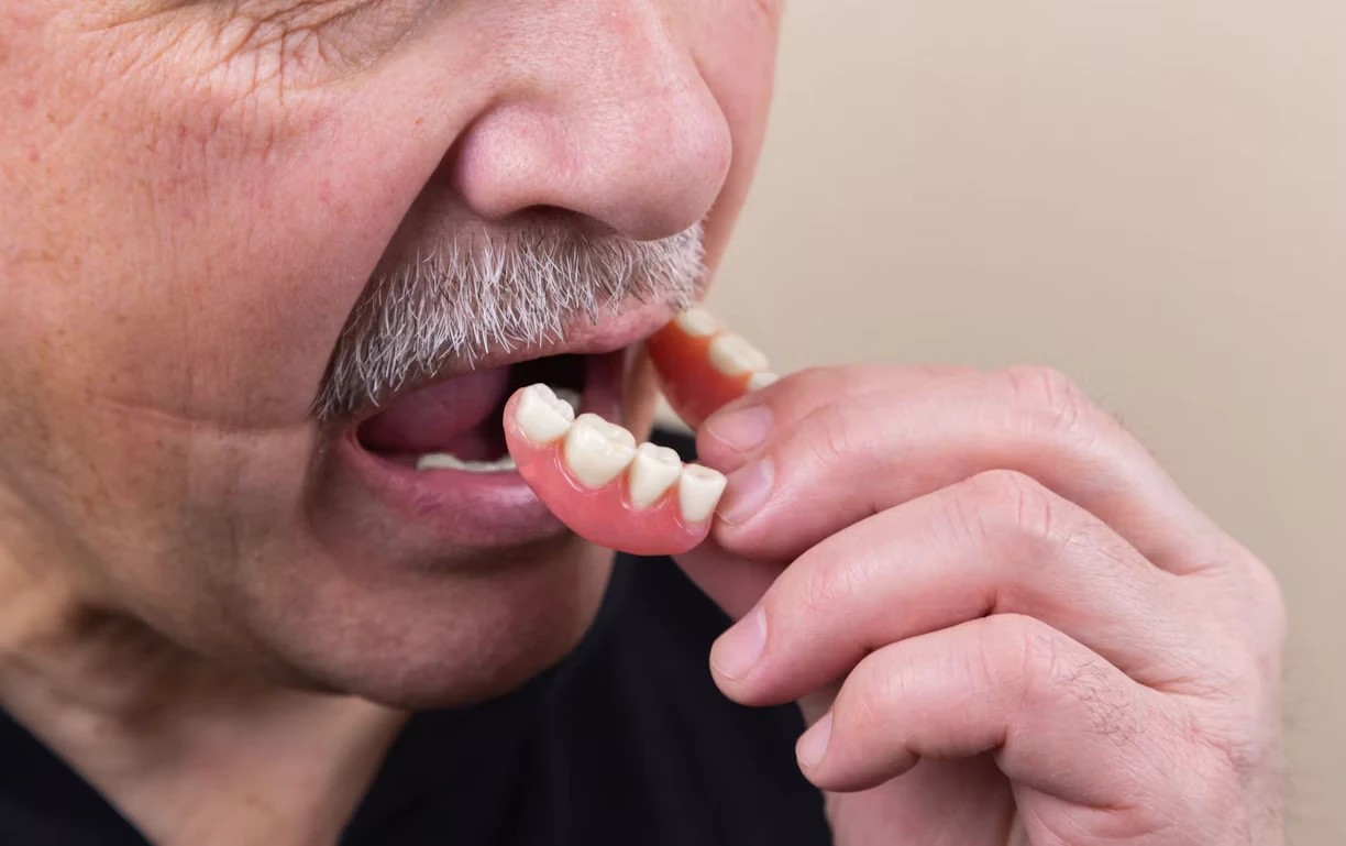 Person removing a loose denture from the mouth